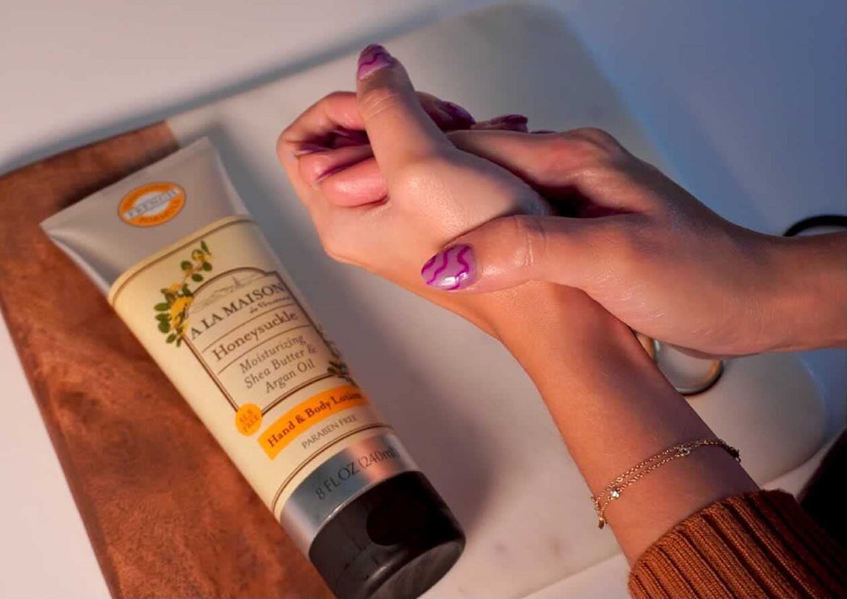Hands applying A LA MAISON Honeysuckle lotion on skin