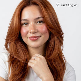 Applying Adore 052 French Cognac on hair for smooth, uniform coverage.