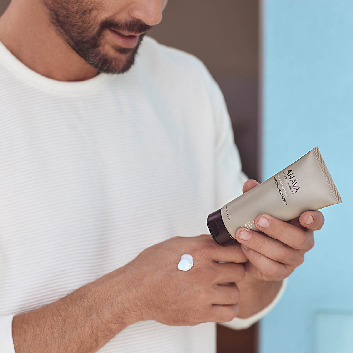 Witch hazel smoothing action visible on AHAVA hand cream surface.