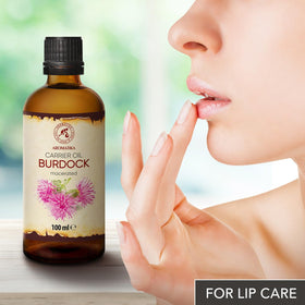 Droplet on fingertip with Burdock Root Oil, suggesting massage-friendly consistency.