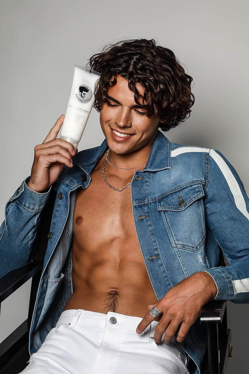 Hands applying Avenue Man curl cream on styled curls.