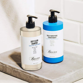 Baxter of California Deep Clean Shampoo bottle pour illustrates dirt and oil removal for refreshed hair