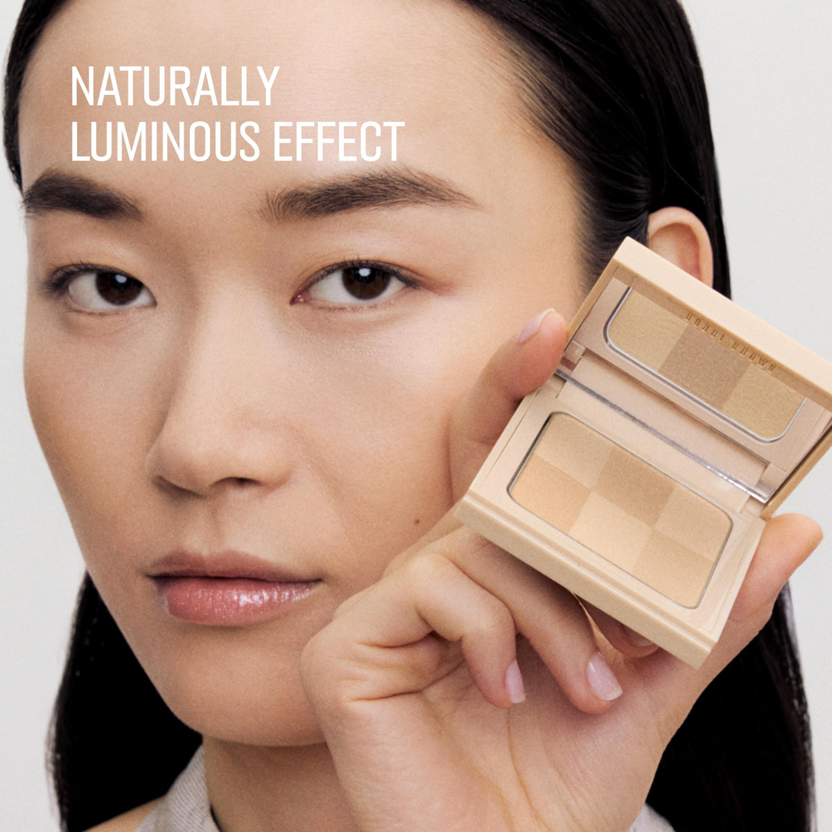Bobbi Brown Nude Finish Illuminating Powder applied on the cheek for natural highlight.