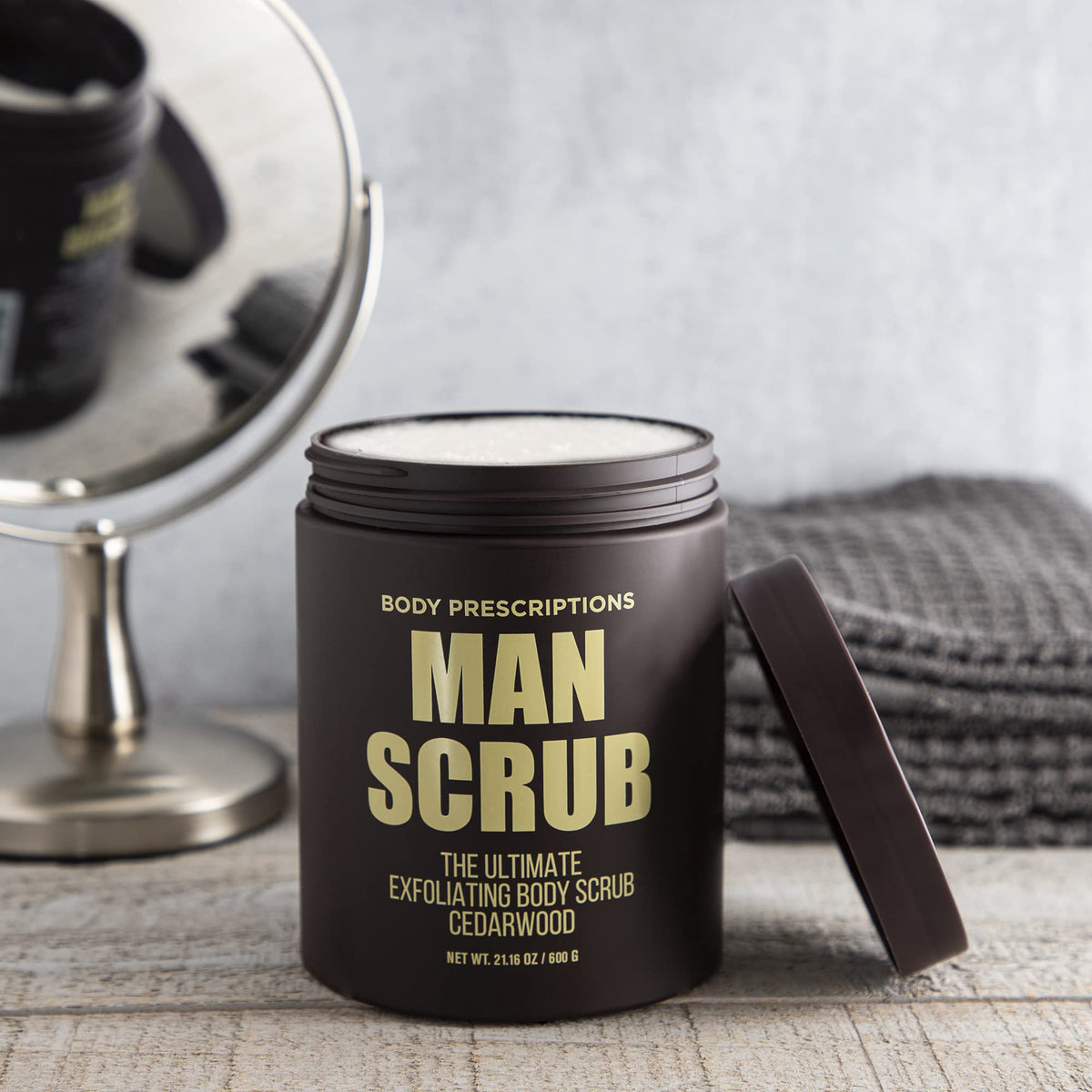 Body Prescriptions cedarwood-scented scrub on bathroom shelf.