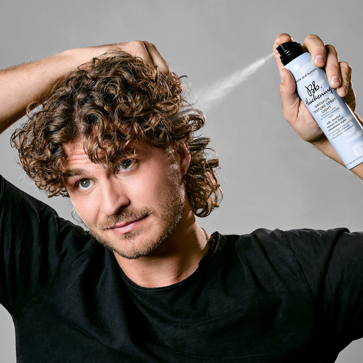 Bumble and bumble texture spray being applied with hands for soft, flexible hold.