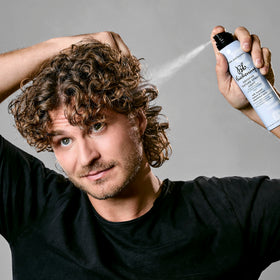 Bumble and bumble texture spray being applied with hands for soft, flexible hold.