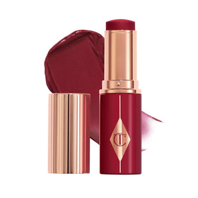 Charlotte Tilbury Unreal Healthy Glow Blush Stick Berry Glow swatch on cheek for luminous, buildable glow.