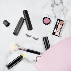 Cositina black lip balm tubes in hand illustrating portable use.