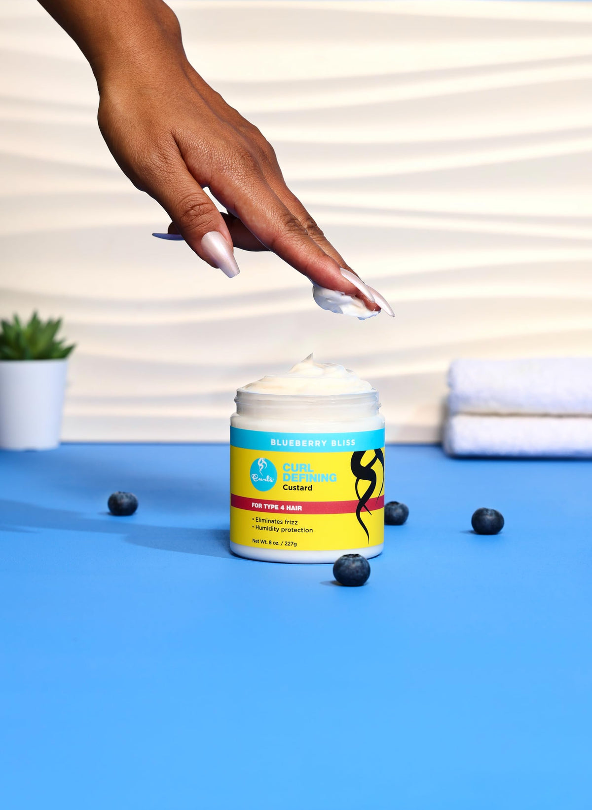 Curls Blueberry Bliss cream bottle closeup highlighting nourishing ingredients for hydration.