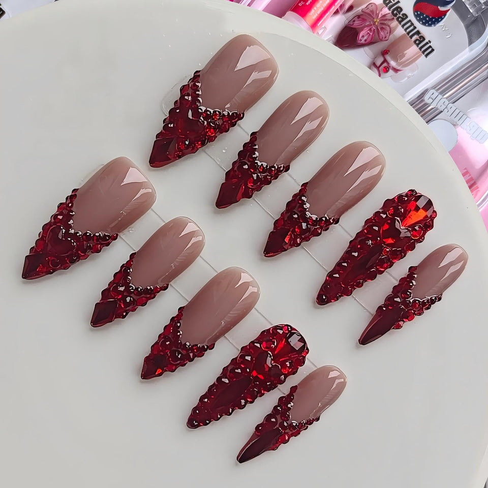 Gleamrain almond press-on nails with nude base and red rhinestones for elegant prom-ready flair.