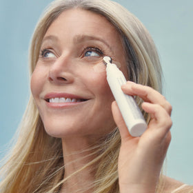 goop Beauty 3x Retinol Eye Lift Serum flat lay with cosmetics for daily routine.