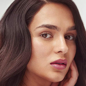Henné Organics lip tint tube in Berry Mauve sits elegant and travel-ready.