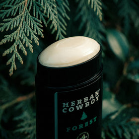 Close-up of Herban Cowboy deodorant showing cedar, mandarin and black pepper notes.