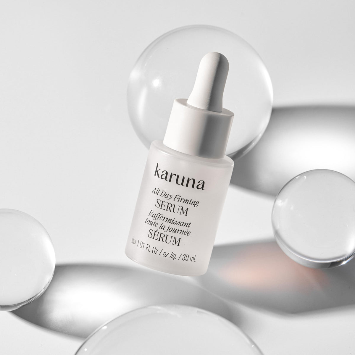Glass bottle reflection of Karuna All Day Firming Serum signaling premium packaging