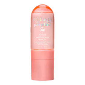 Kopari Paradiso Sun Juice SPF 30 bottle on a sunlit beach for easy SPF application.