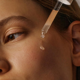 Applying 2–3 drops of Korres Serum to face and neck in routine