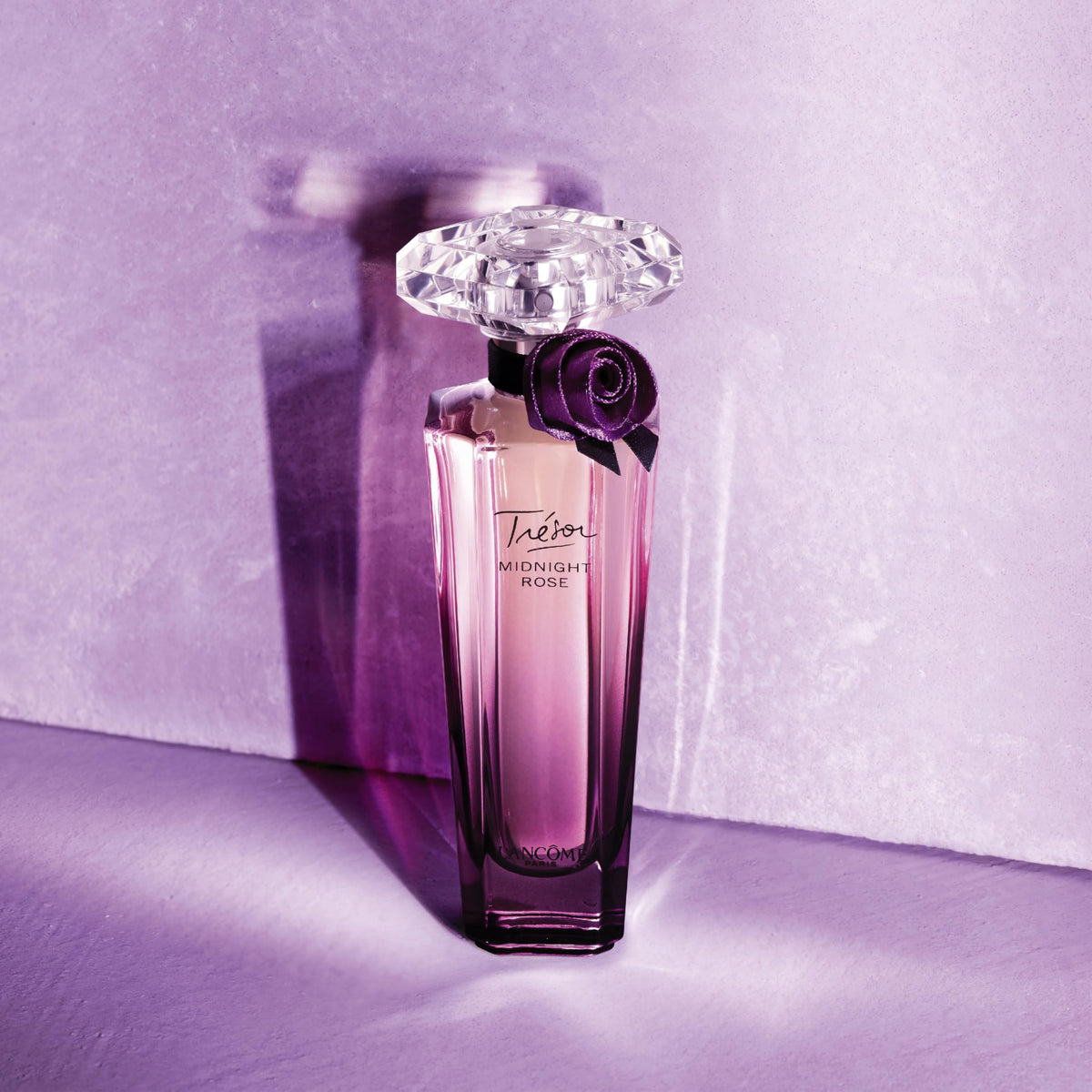 Lancôme Trésor Midnight EDP bottle on vanity with soft lighting.