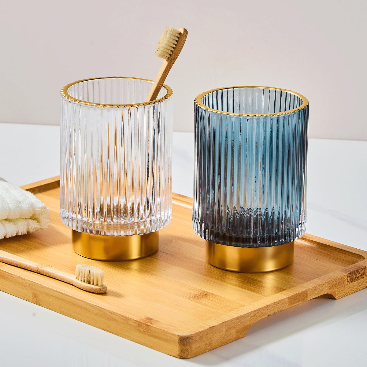LEICURACE glass toothbrush holder with gold base on the vanity.