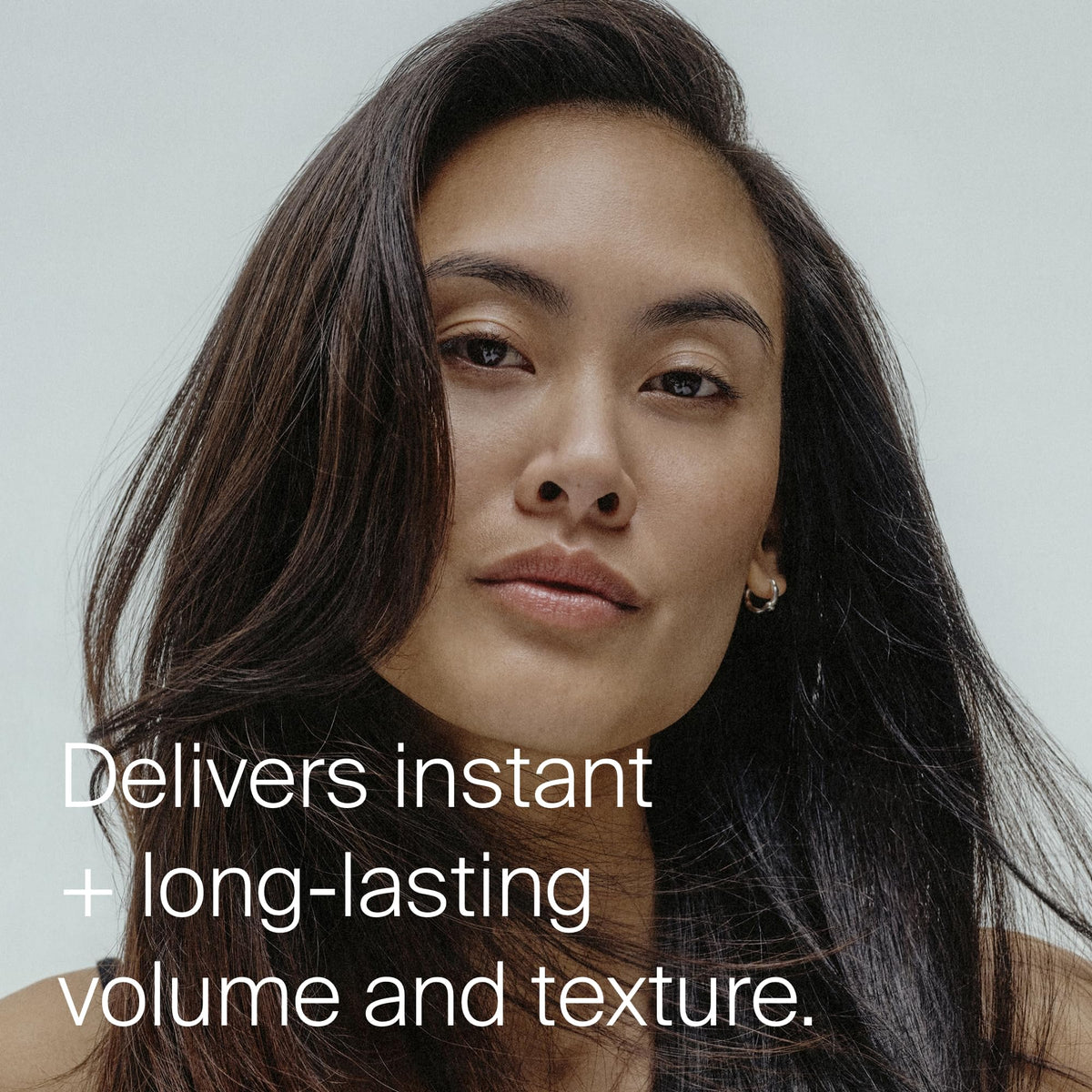 Hands applying Living Proof spray for buildable grip and dry styling.
