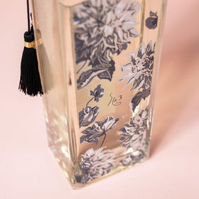 LOLLIA Elegance bottle close-up with gold tassels and sleek glass, a tub-side centerpiece.