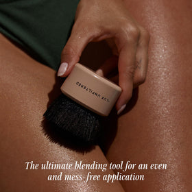 Lux Unfiltered self-tanner brush held for controlled, streak-free blending.