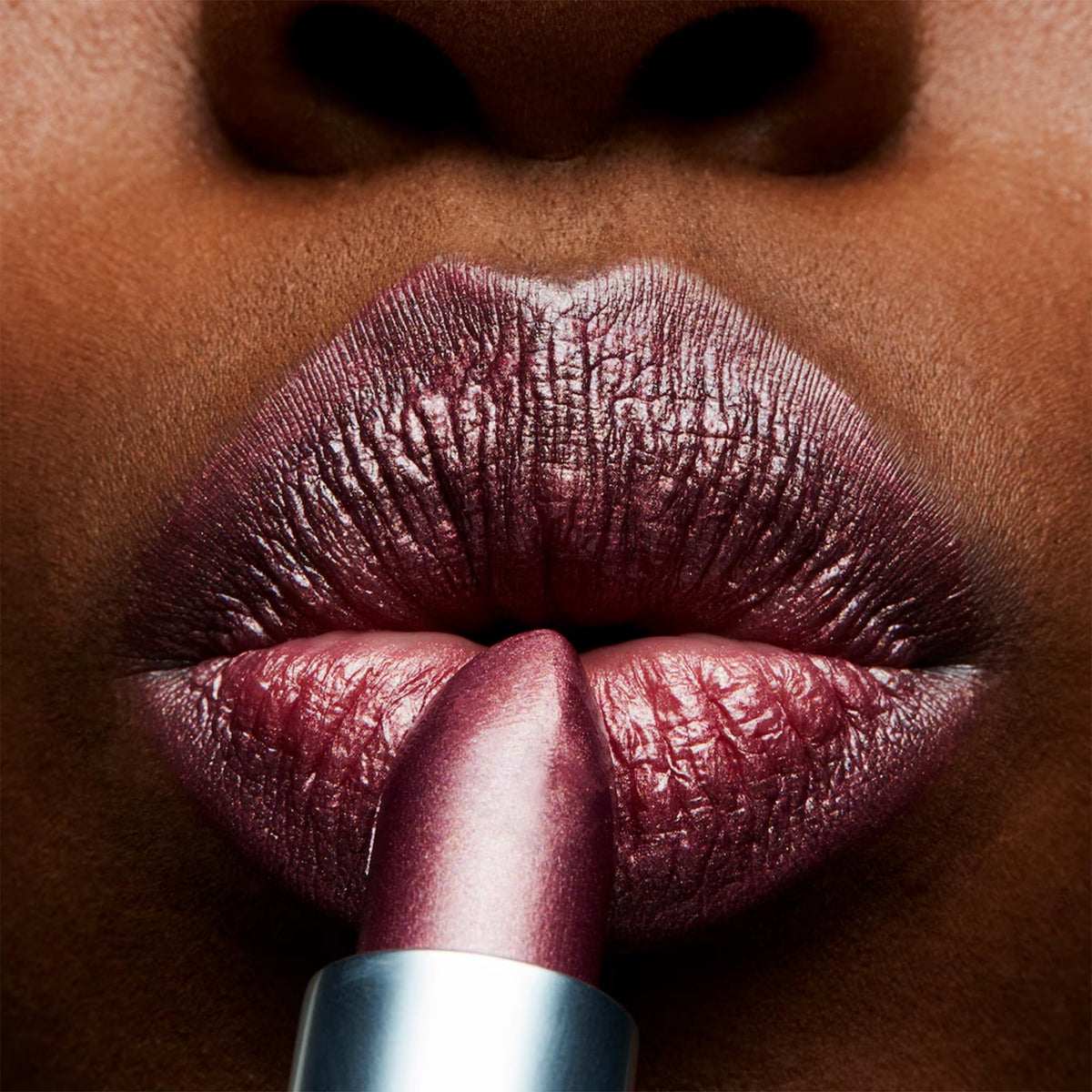 MAC Frost Lipstick Plum Dandy swatch on arm demonstrates buildable color for everyday or evening looks.