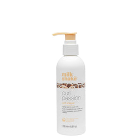 Milk Shake Curl Passion bottle with pump pouring to define curls.