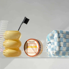 Mizani Artful Edges bottle closeup highlights castor oil and shea butter ingredients.