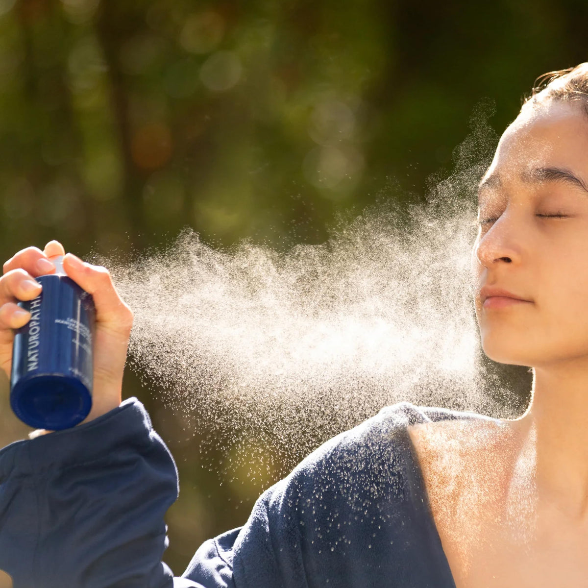 Hand holds Naturopathica mist for daily refresh.