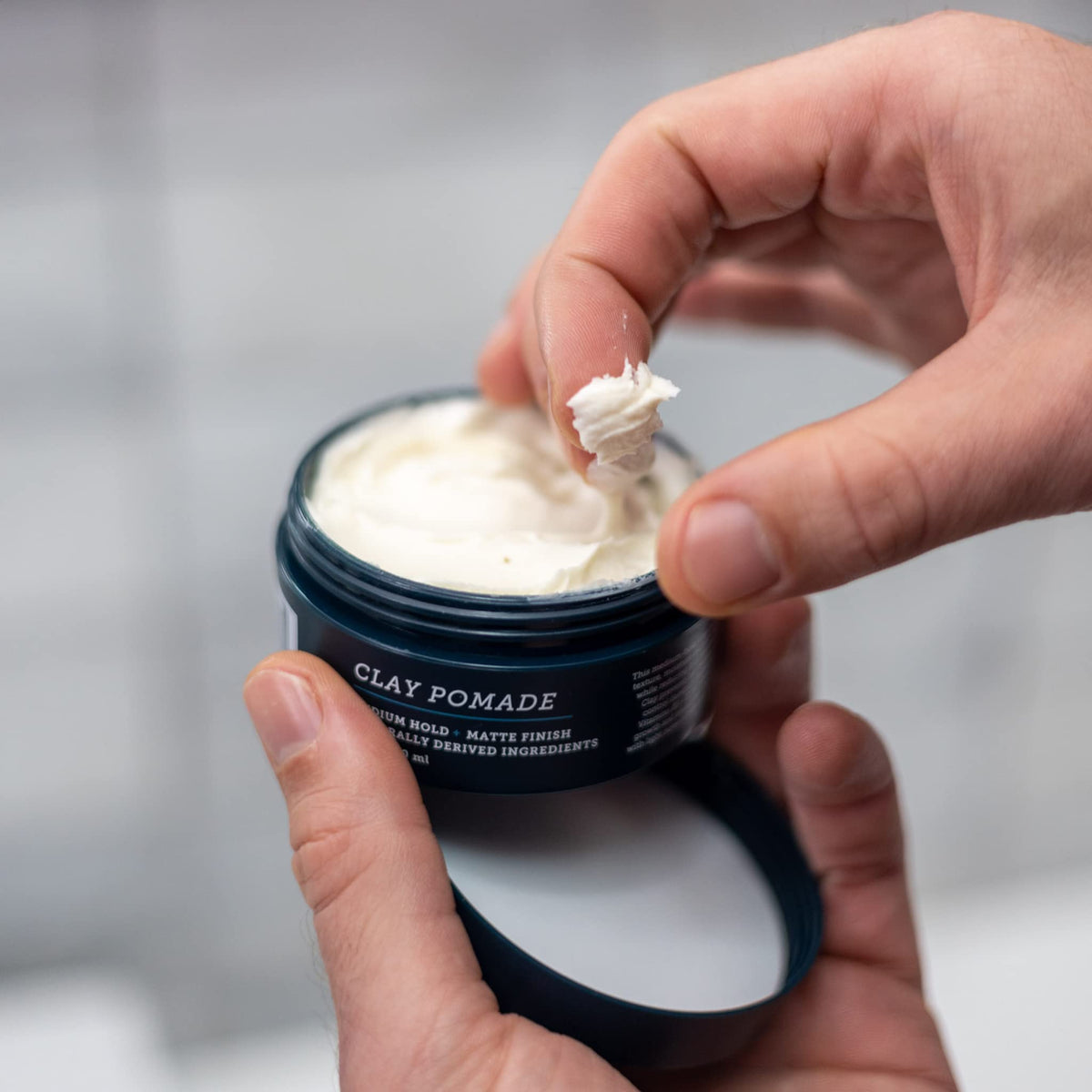 Oars + Alps hands applying pomade for touchable, frizz-free control.
