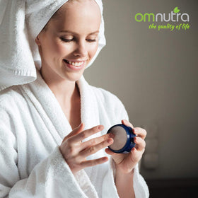 Hands applying OmNutra OncoEase moisturizer for dry skin care.