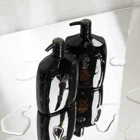 Lifestyle shot showing Oribe Signature Shampoo on a bathroom shelf for salon-grade results