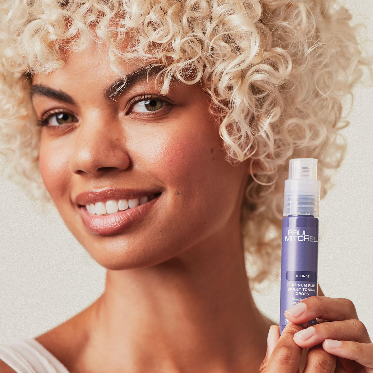 In-hand view of violet-toning drops ready to blend with hair care