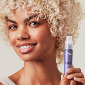 In-hand view of violet-toning drops ready to blend with hair care