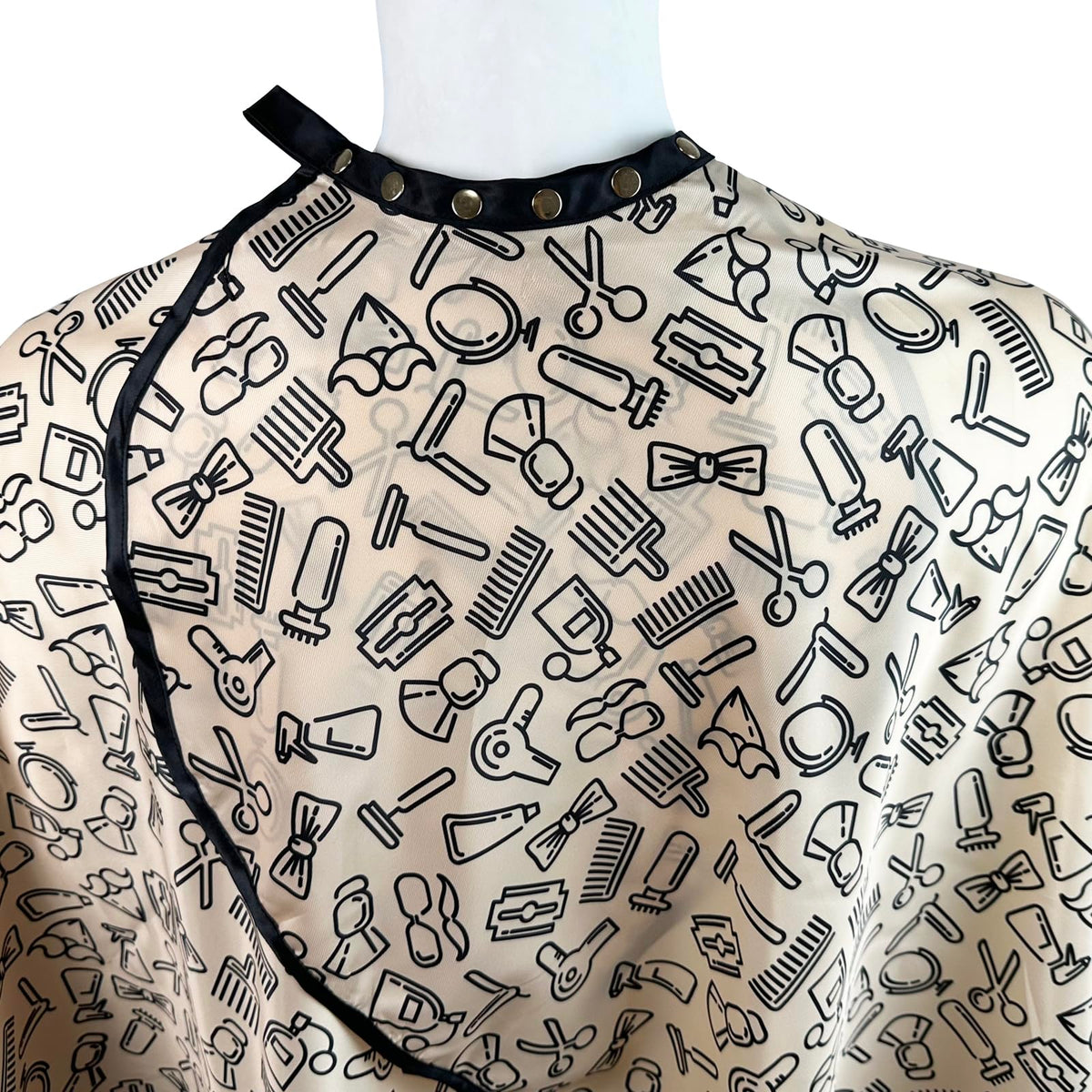 Pelocapa barber cape snap closures close-up highlights adjustable fit.