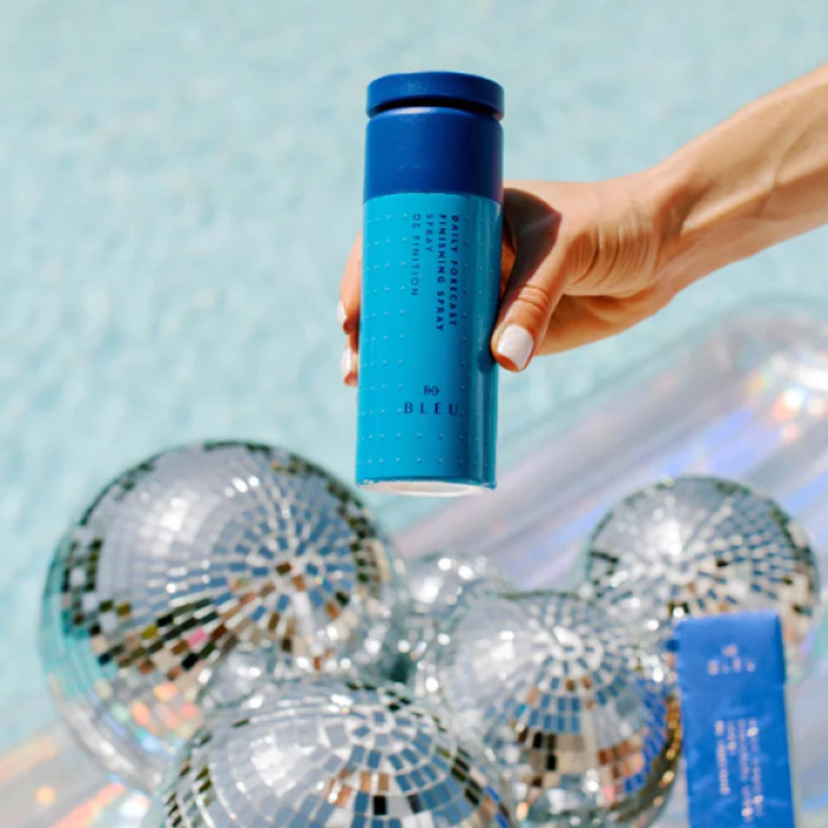 R+Co BLEU user applying finishing spray to lock the look in place.