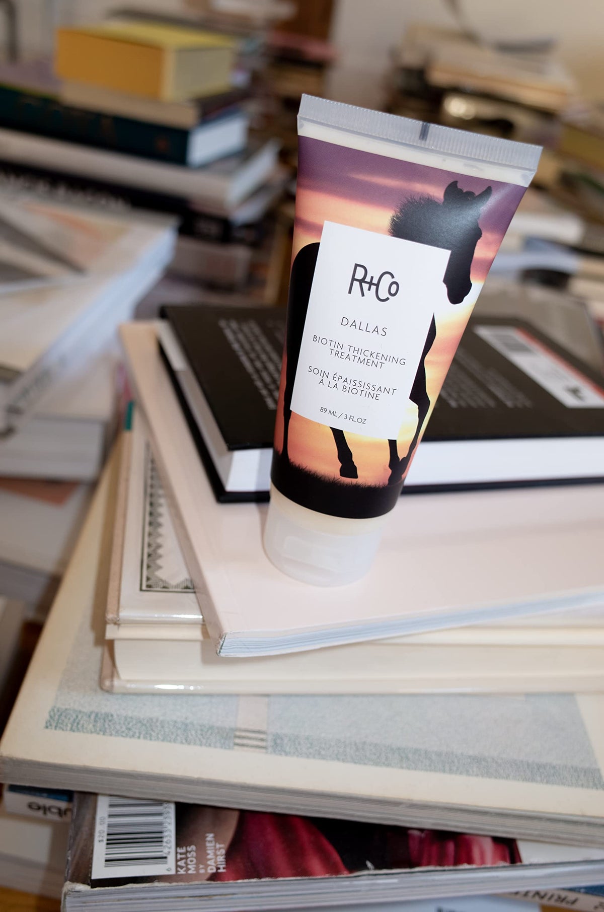 Hands applying R+Co Dallas Biotin Thickening Treatment for fuller texture