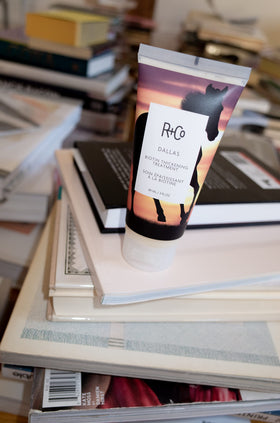 Hands applying R+Co Dallas Biotin Thickening Treatment for fuller texture