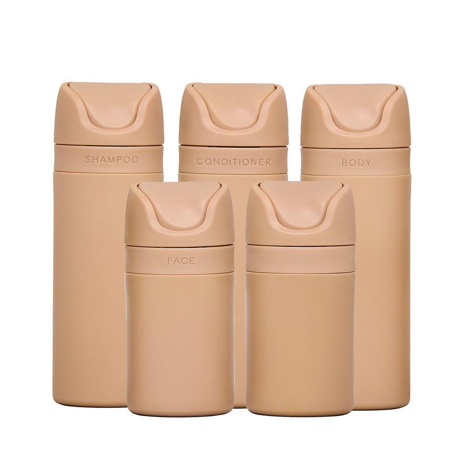 RIES essential refillable toiletry bottles set in sand, airless pumps reduce leaks during travel