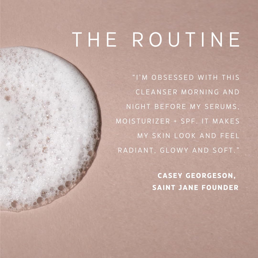 Saint Jane Pore Clarity Cleanser bottle beside hibiscus blossoms showing AHAs for gentle resurfacing.