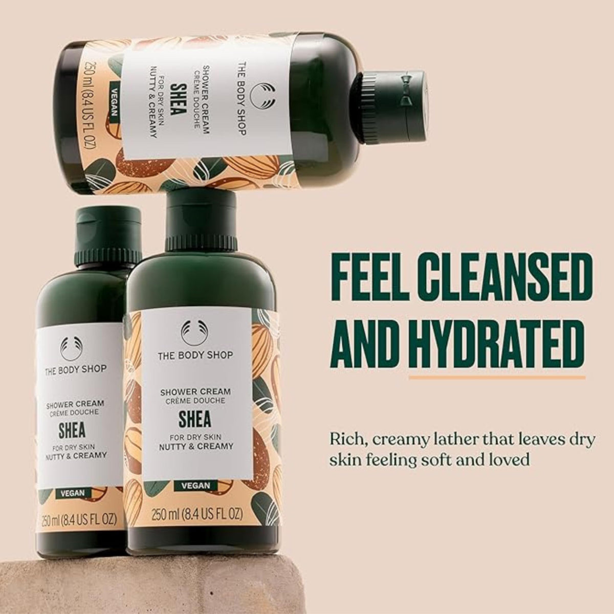 The Body Shop Shea Shower Cream bottle next to towel showing creamy lather