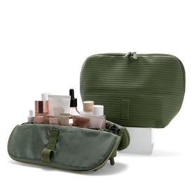 THE VERTI olive medium vertical bag open, showing organized pockets for skincare and toiletries