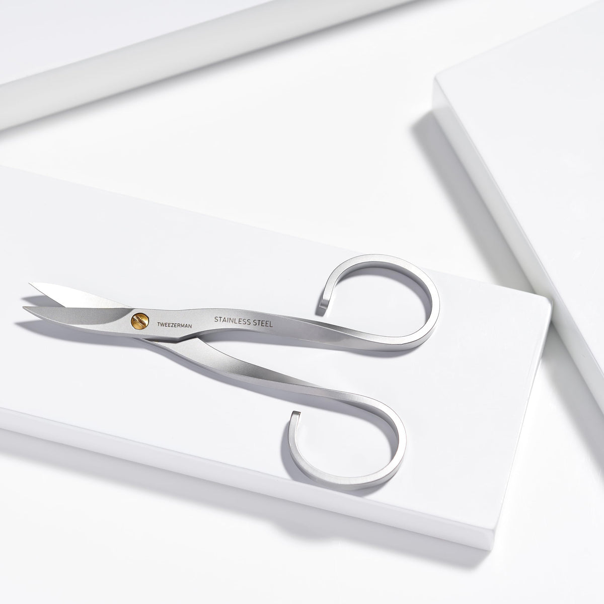 Tweezerman stainless steel nail scissors in use cutting a nail with precision.
