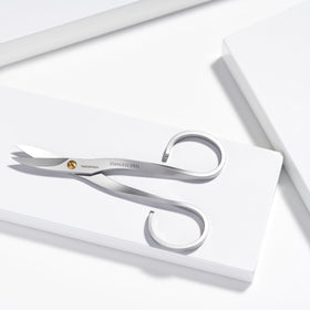 Tweezerman stainless steel nail scissors in use cutting a nail with precision.
