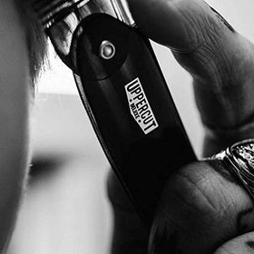 Uppercut Deluxe pomade being applied with a comb for precise side part