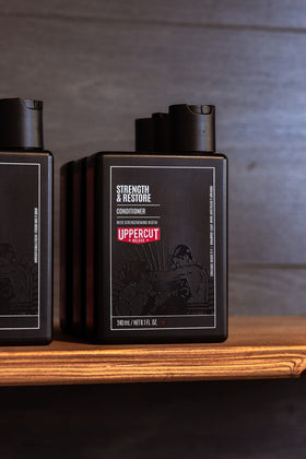 Uppercut Deluxe Strength & Restore on bathroom shelf with other grooming products