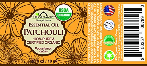 US Organic Patchouli Oil drops resting on wood suggest versatile aroma for diffusion and blends.