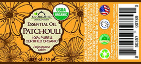 US Organic Patchouli Oil drops resting on wood suggest versatile aroma for diffusion and blends.