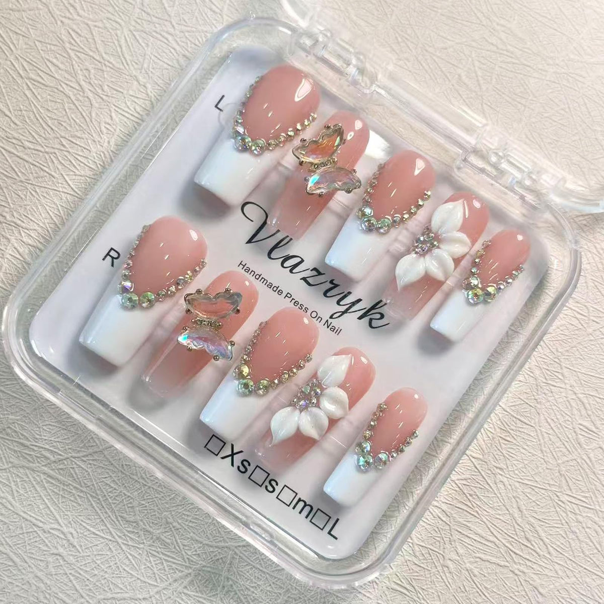 Vlazryk luxury nails with long square white tips and rhinestones for a quick, elegant manicure.