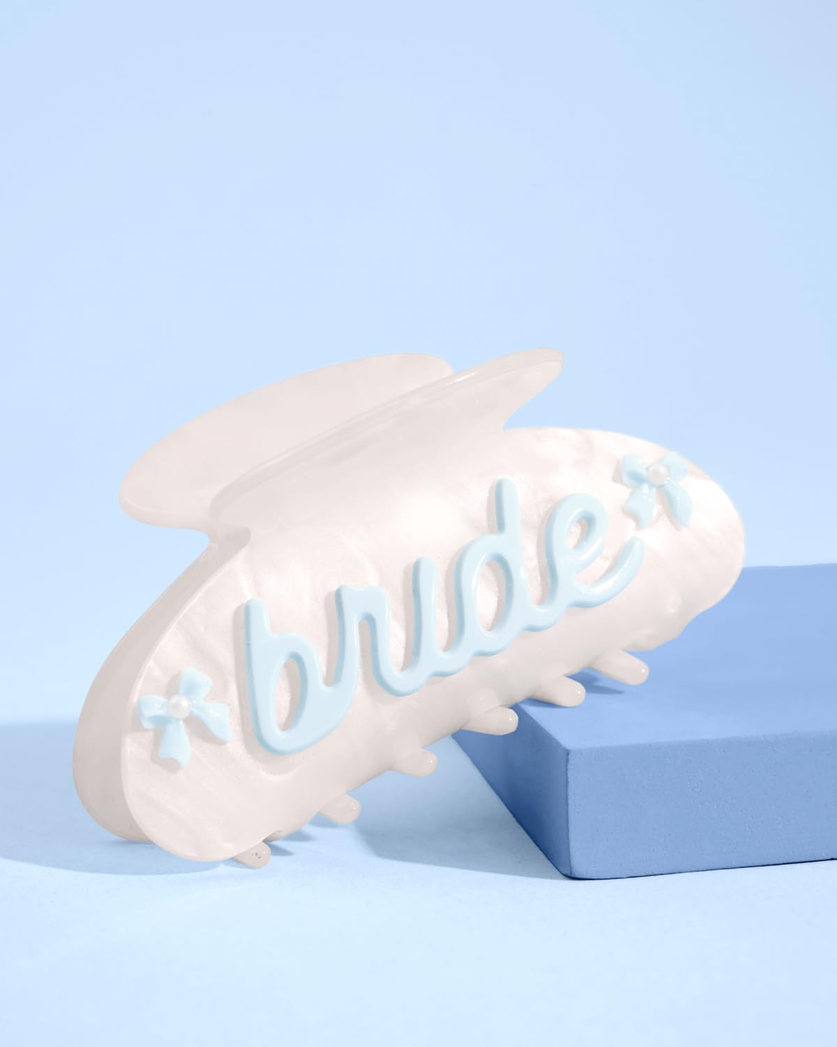 xo Fetti Bride Claw Clip shows blue bows and pearl details on marble acrylic.
